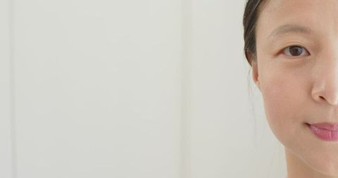 Minimal closeup headshot asian woman gazing and smiling with generous left copy space