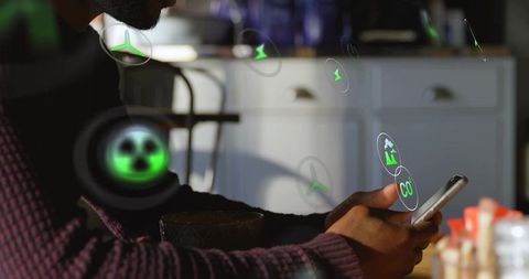 Man holding smartphone with augmented reality eco icons on kitchen showing co2 data