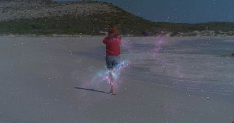 Woman walking on beach with cosmic aura and starscape sky