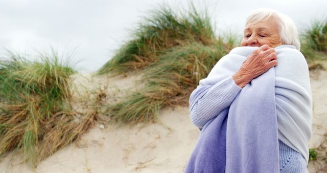 Senior Woman Wrapped in Blanket on Beach Dunes on Cloudy Day - Download Free Stock Images Pikwizard.com