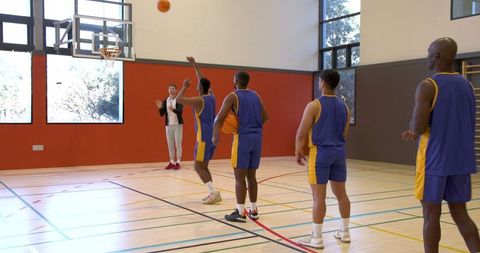 Diverse Basketball Team Practicing Free Throws in Indoor Gymnasium
