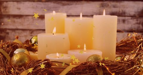 Elegant holiday candles surrounded by festive baubles and glowing stars