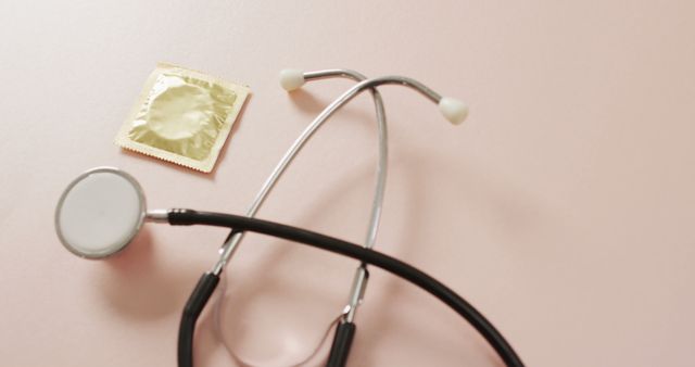Image of close up of stethoscope with condom on pink background. global medicine and healthcare concept.