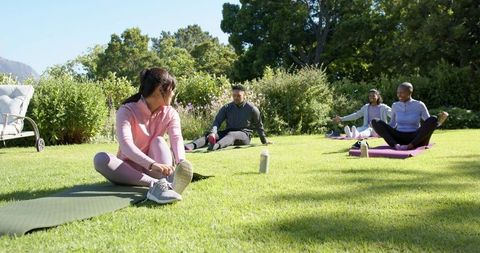 African american friends stretching together on sunlit garden lawn for outdoor fitness