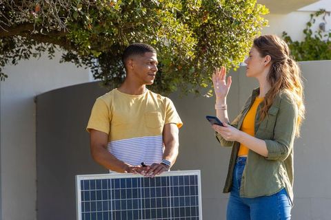 Discussing residential solar panels, diverse neighbors collaborating on sustainable energy