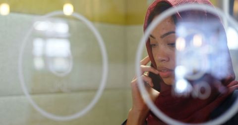 Thoughtful Businesswoman in Hijab Using Smartphone at Work