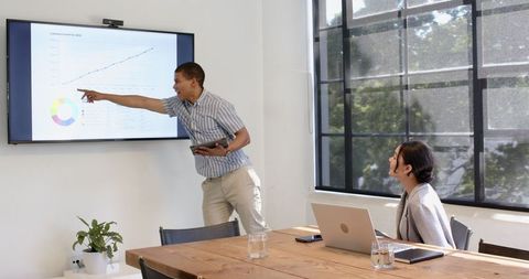 Businessman Presenting Data to Colleague in Modern Office Meeting