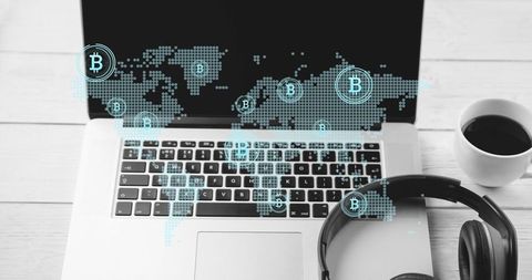 Projecting laptop displaying global bitcoin network over minimalist home workspace with headphones