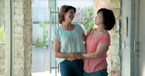 Senior multiracial friends smiling and embracing at front door