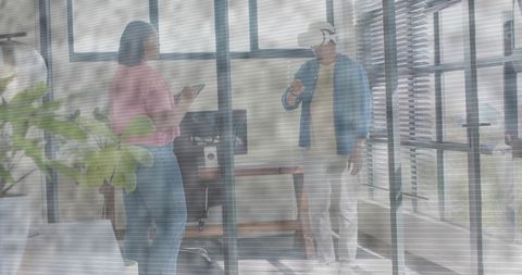 Coworkers collaborating with vr headset and smartphone in modern glass office