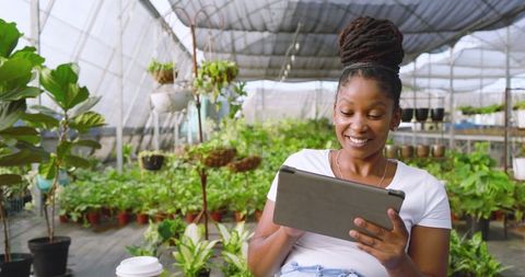 Woman Using Tablet in Peaceful Greenhouse Setting