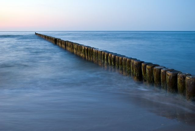 Wooden Breakwater Extends Into Calm Sea at Sunset - Download Free Stock Photos Pikwizard.com
