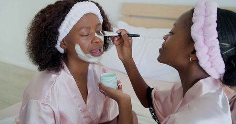 Mother daughter home spa night applying mint facial mask bonding in pink robes