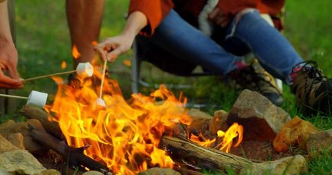 Couple Roasting Marshmallows Over Campfire at Grassy Campsite Cozy Rustic Camping Moment