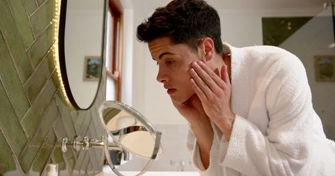 Young Man Conducting Daily Skincare Routine in Modern Bathroom