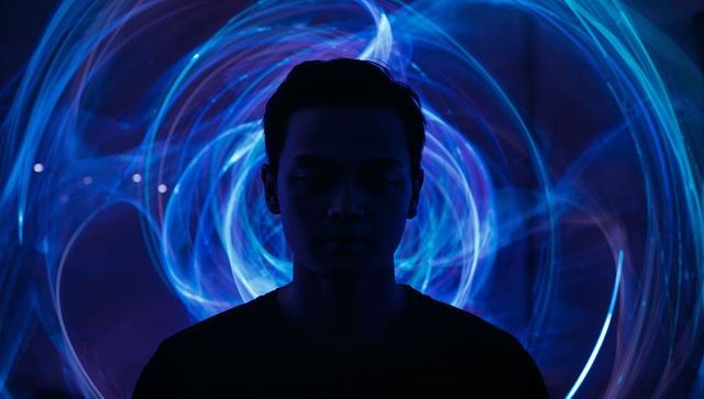 Silhouetted man standing surrounded by neon blue vortex lightpainting futuristic concept