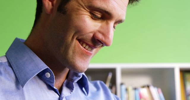 Smiling Man in Blue Shirt Reading in Home Office - Download Free Stock Images Pikwizard.com