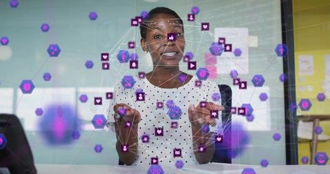 Businesswoman gesturing while manipulating holographic network of purple hexagon icons