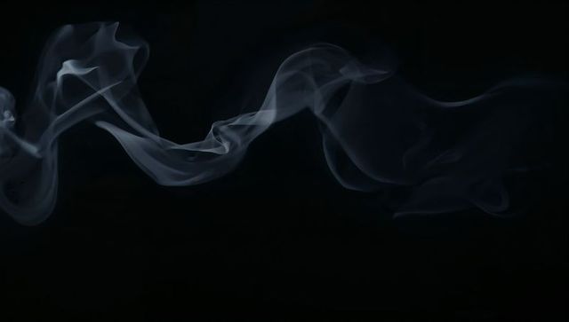Floating blue-gray smoke ribbon curling across black background, vapor abstract