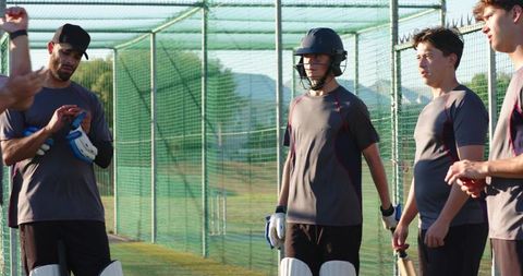 Cricket nets practice with batter wearing helmet and pads during team training session
