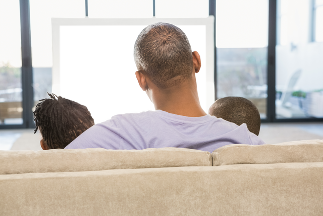 Transparent family sitting on sofa from behind watching television together at home - Download Free Stock Videos Pikwizard.com