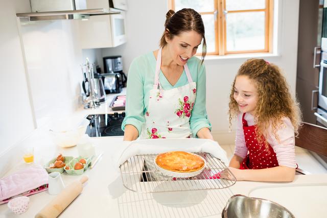 Mother interacting with daughter while holding pancake in cooling rack - Download Free Stock Photos Pikwizard.com