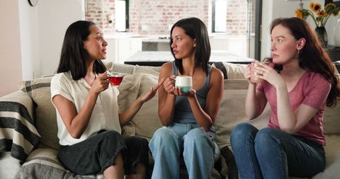 Joyful Friends Celebrating Pregnancy over Tea in Cozy Living Room