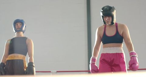 Two Female Boxers Standing Ready in Ring Wearing Headguards and Boxing Gloves Sparring