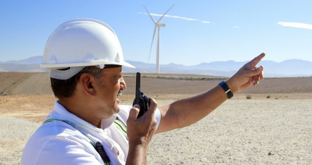 Engineer Communicating with Walkie-Talkie Near Wind Turbine in Rural Area - Download Free Stock Images Pikwizard.com