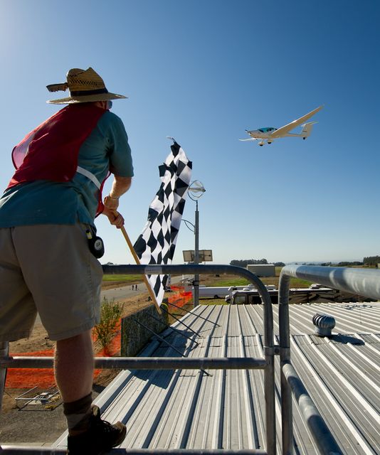 CAFE Foundation Hanger Boss Mike Fenn waves the speed competition checkered flag for the PhoEnix aircraft during the 2011 Green Flight Challenge, sponsored by Google, at the Charles M. Schulz Sonoma County Airport in Santa Rosa, Calif. on Thursday, Sept. 29, 2011. NASA and the Comparative Aircraft Flight Efficiency (CAFE) Foundation are having the challenge with the goal to advance technologies in fuel efficiency and reduced emissions with cleaner renewable fuels and electric aircraft. Photo Credit: (NASA/Bill Ingalls)