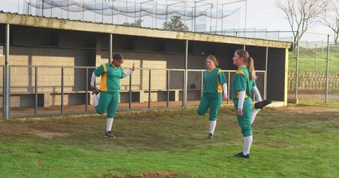 Female softball players stretching before outdoor game