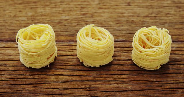 Three nests of dry spaghetti resting on a rustic wooden table, ideal for concepts related to pasta cooking, Italian cuisine, and food preparation. Perfect for recipe blogs, culinary websites, and kitchen decor visuals.