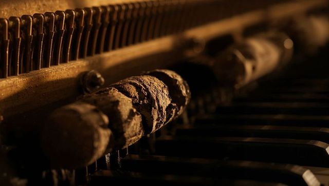 Crumbling piano hammers revealing vintage action decay in warm amber macro light
