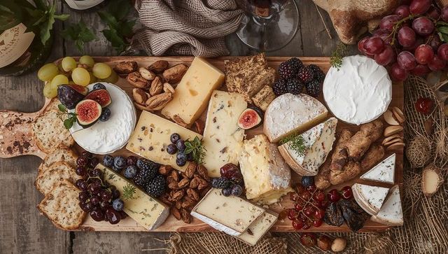 Displaying rustic cheese and charcuterie board with figs, grapes, crackers, nuts