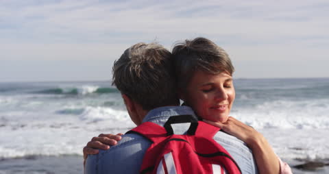 Retired Couple Embracing by Ocean Waves in Sunlit Joy