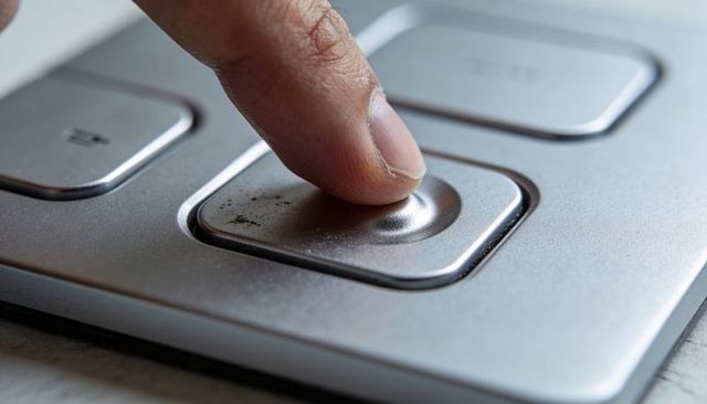 Macro fingertip pressing concave brushed metal control button, dirt and tactile texture