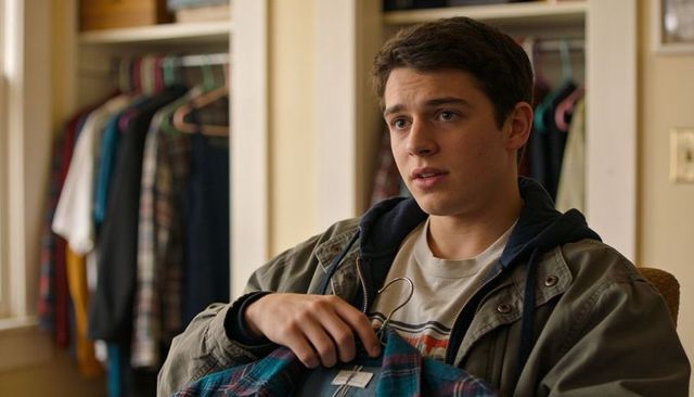 Teen holding plaid shirt while choosing casual outfit in bedroom closet