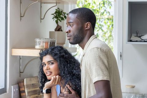 Sunlit kitchen embrace: indian woman and african american man sharing quiet morning moment