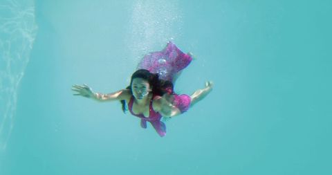 Elegant Woman in Red Evening Dress Swimming Underwater in Pool