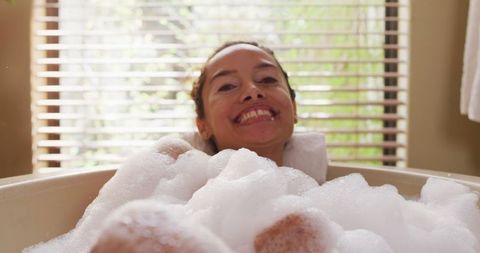 Happy woman enjoying bubble bath relaxation at home