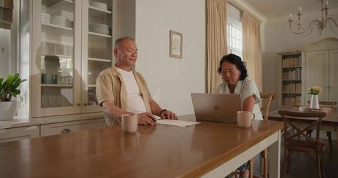 Senior Couple Discussing Finances at Home with Laptop and Coffee