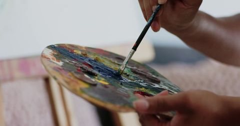 Artist mixing blue paint on wooden palette with brush closeup creative studio