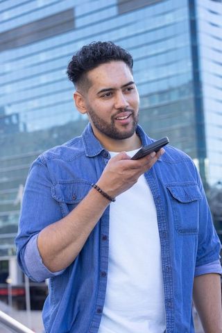 African american man speaking into smartphone outdoors in urban business district