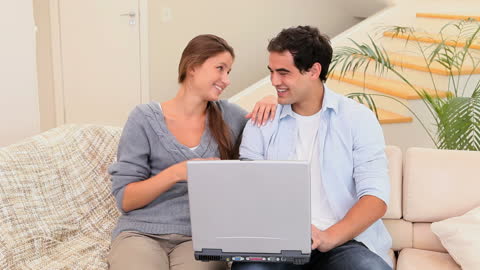 Smiling Couple Relaxing Together with Laptop on Couch