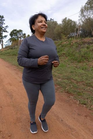 Senior woman staying active with jogging in rural landscape