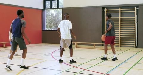 Young men practicing indoor basketball drill, dribbling and faking on gym court