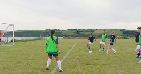 Teen athletes practicing soccer with team on outdoor field