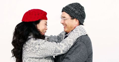 Joyful middle-aged asian couple embracing with smiles