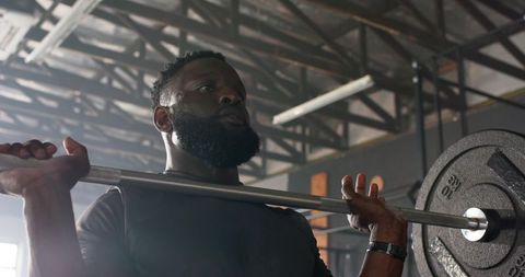 African american man lifting barbell in industrial gym