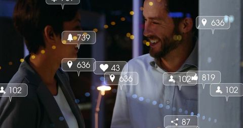 Colleagues networking by office window at night showing social media interaction overlays